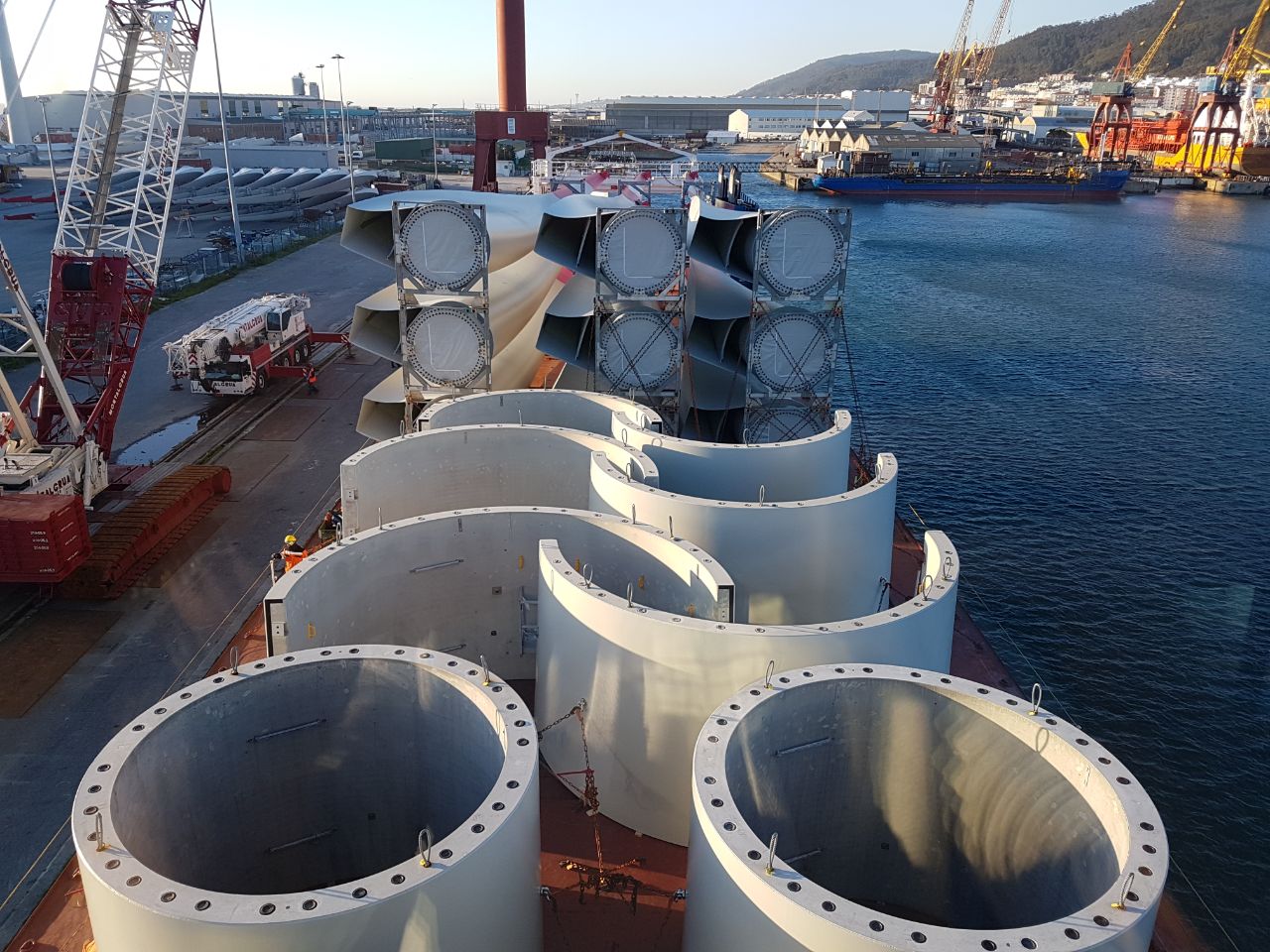 Turmsektionen und Flügel von Windkraftanlagen auf einem Schiff im Hafen