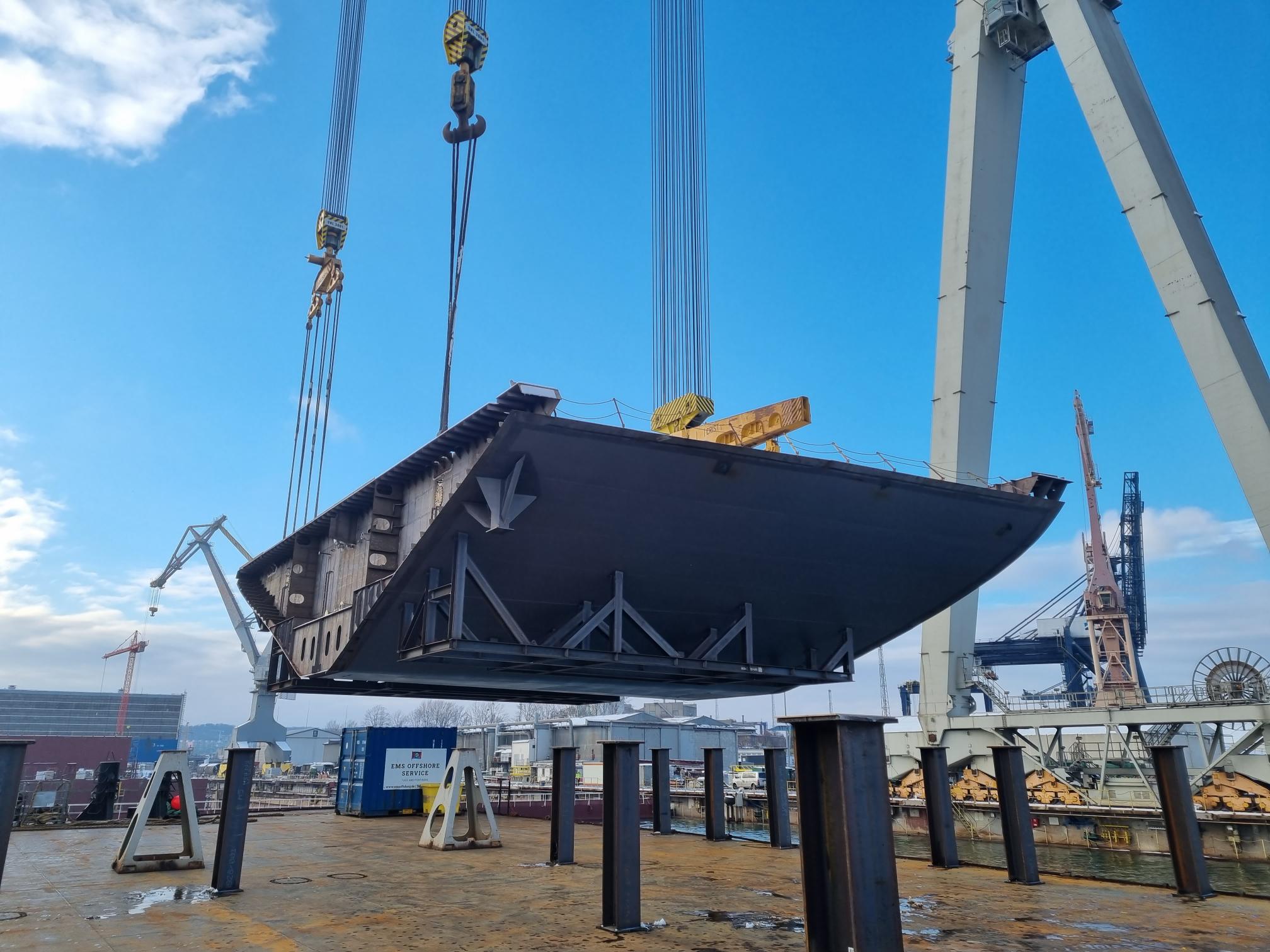 Hull section of a cruise ship is lifted from a pontoon with the help of a crane on board